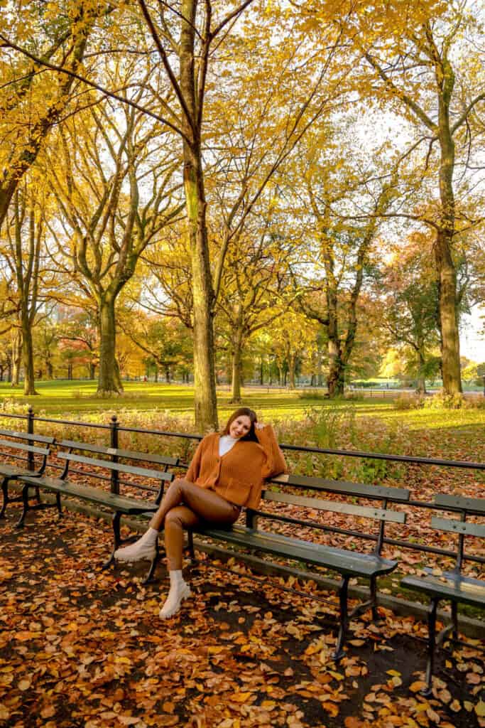 girl sitting on park bench in central park during fall season
