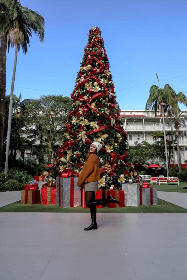 girl posing in front of hotel del coronado christmas tree in courtyard