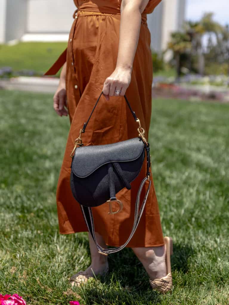 girl holding the dior saddle bag wearing an orange dress