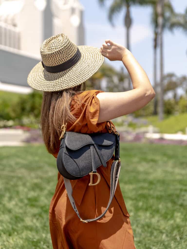 women outdoors holding a black handbag in an orange dress