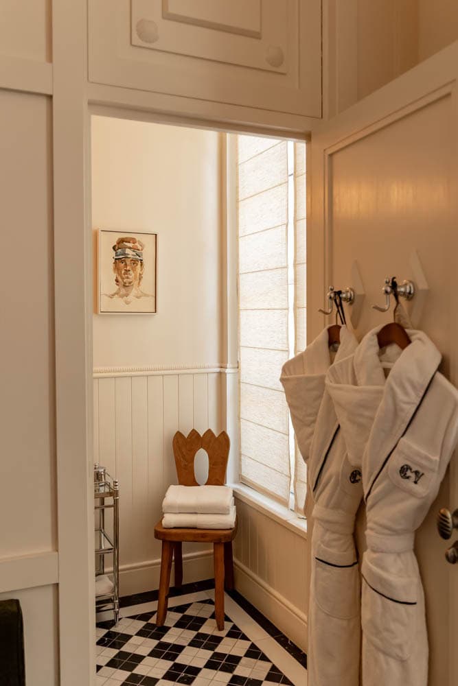 checkered floor bathroom with two luxe robes hanging on the door