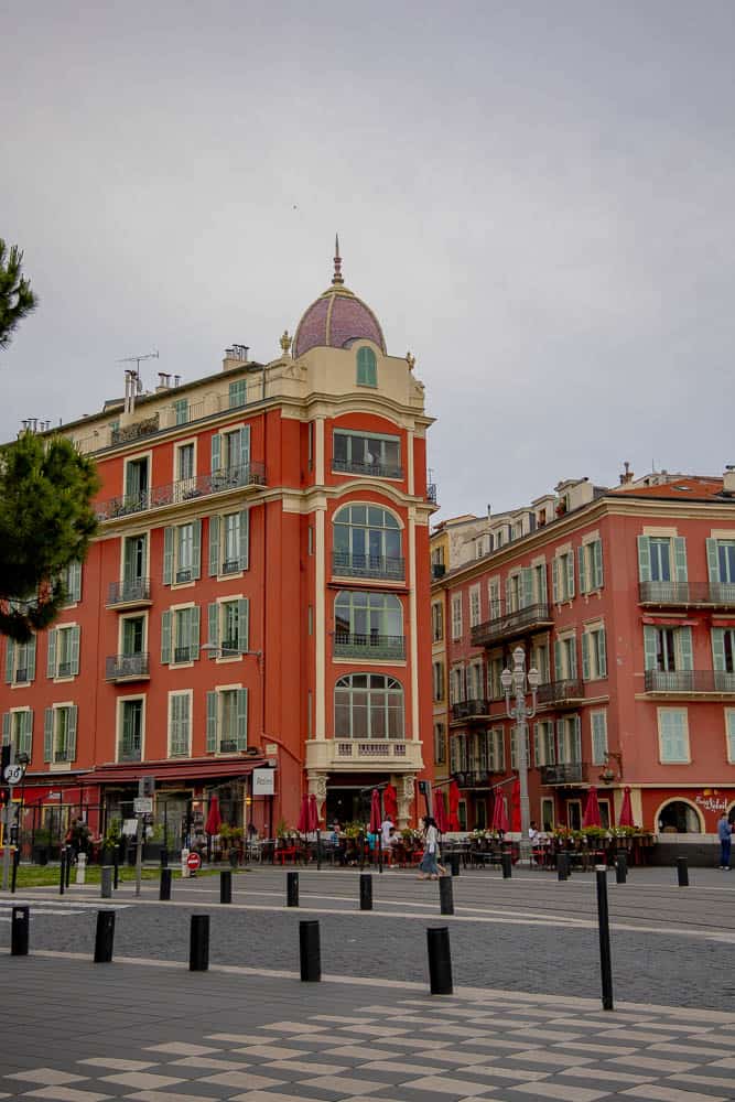 Elegant European-style building with a domed tower in a vibrant cityscape.