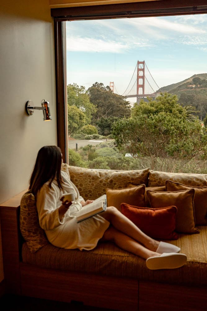 woman sitting near window with a view of the Golden Gate Bridge in hotel