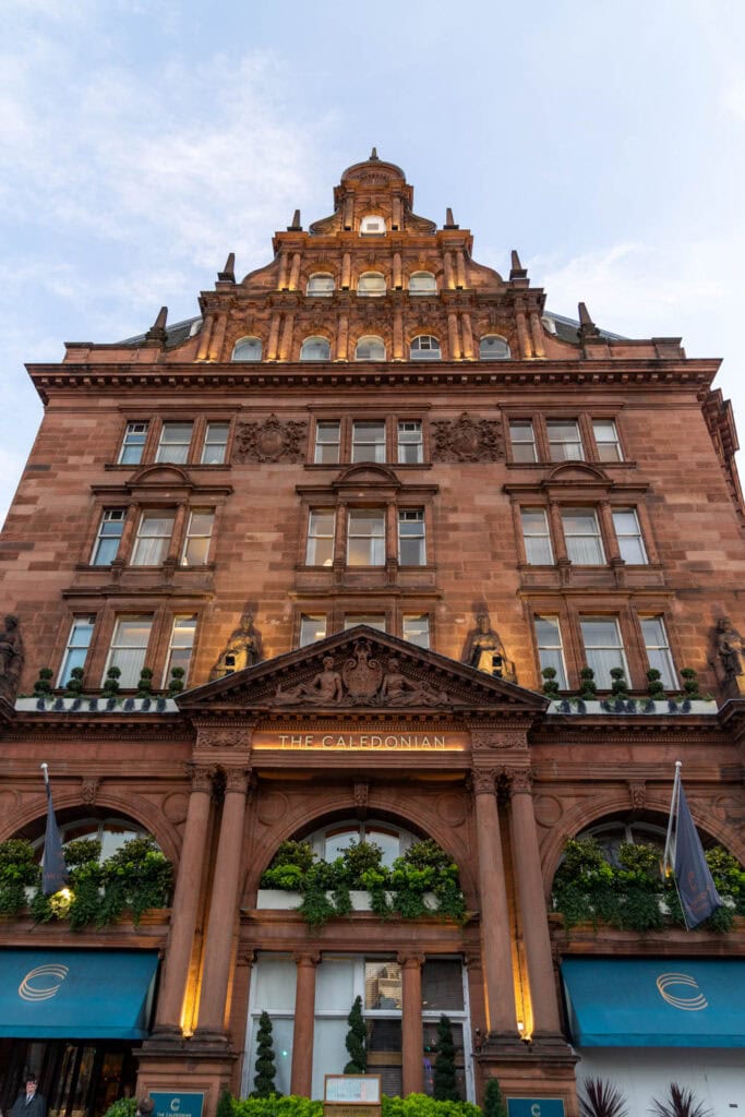 Luxurious hotel facade at dusk, historical architecture with elegant lighting and lush greenery.