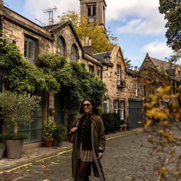 Charming woman walking on cobblestone street with historic buildings and church tower in the background.