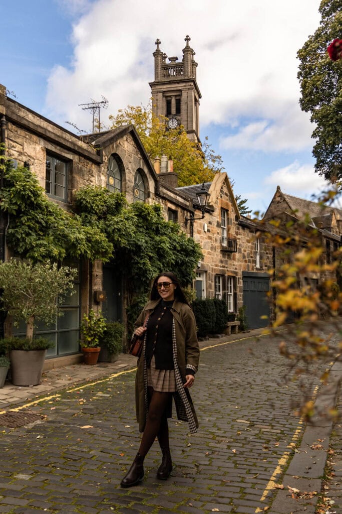 Charming woman walking on cobblestone street with historic buildings and church tower in the background.