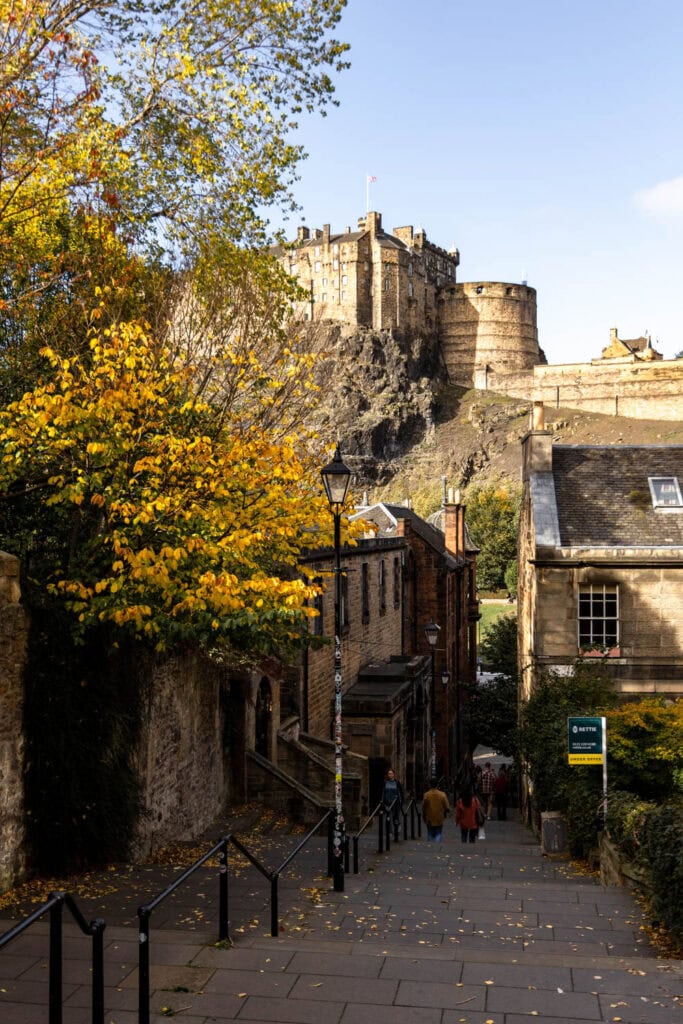 Scenic view of Edinburgh Castle perched on Castle Rock with autumn foliage in the foreground.