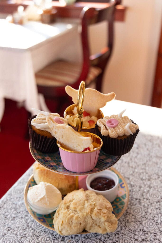 A beautifully arranged afternoon tea with scones, cupcakes, and jam on a decorative tiered tray, ideal for a luxurious tea experience.