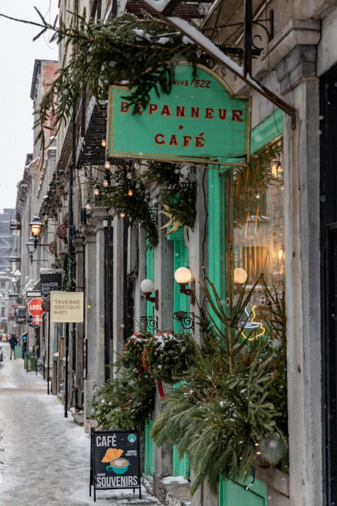 Exterior view of a cozy Montreal café with festive holiday decorations and greenery.
