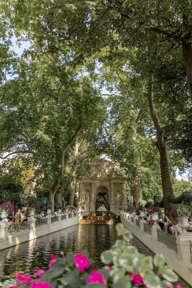 Famous Serenity Fountain surrounded by tall trees and vibrant flowers in a peaceful park scene.