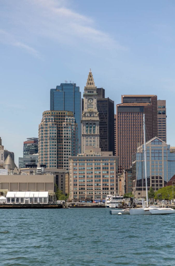 Boston skyline with historic buildings and harbor in the foreground.