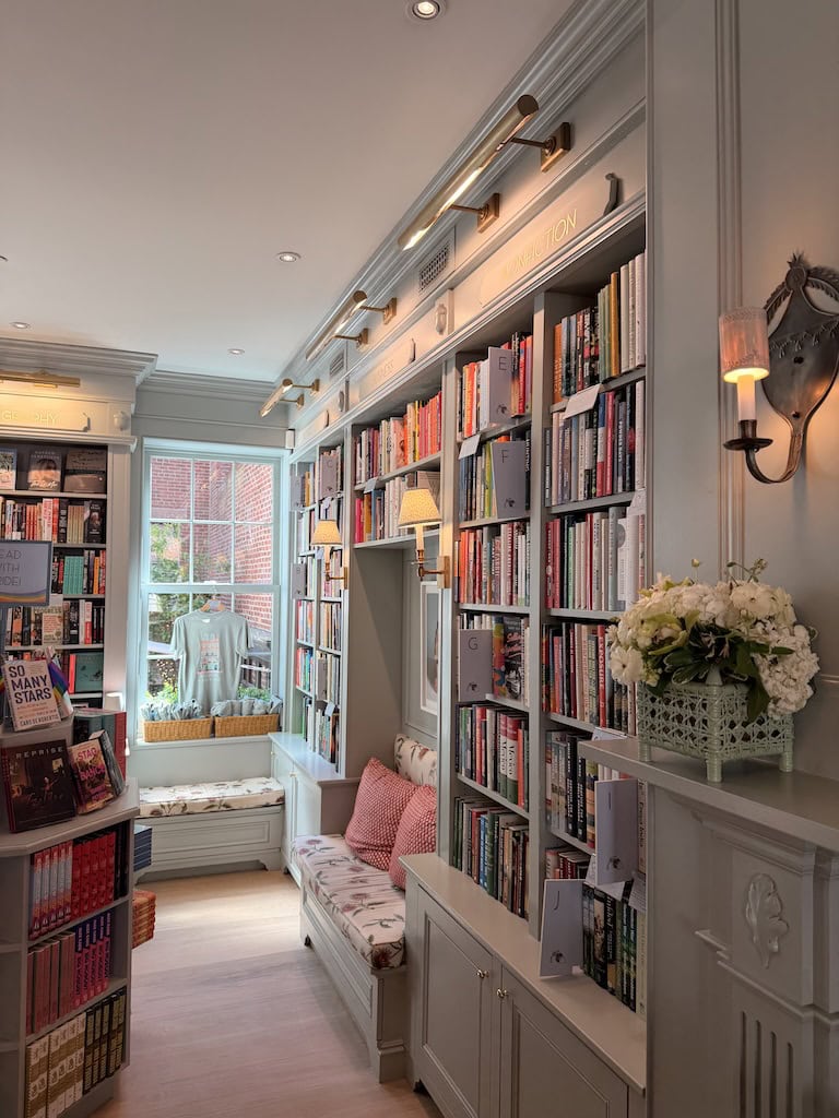 Charming bookshop with built-in bookshelves, window seat, and soft lighting.