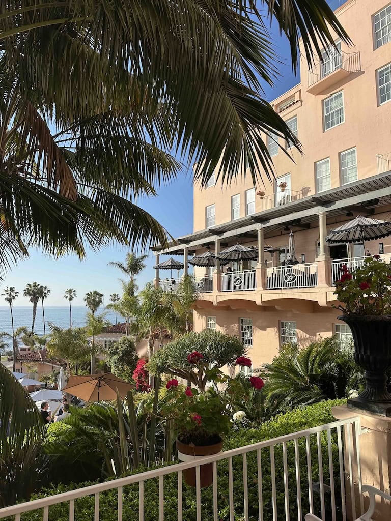 Elegant hotel balcony overlooking lush tropical garden and ocean in the background.