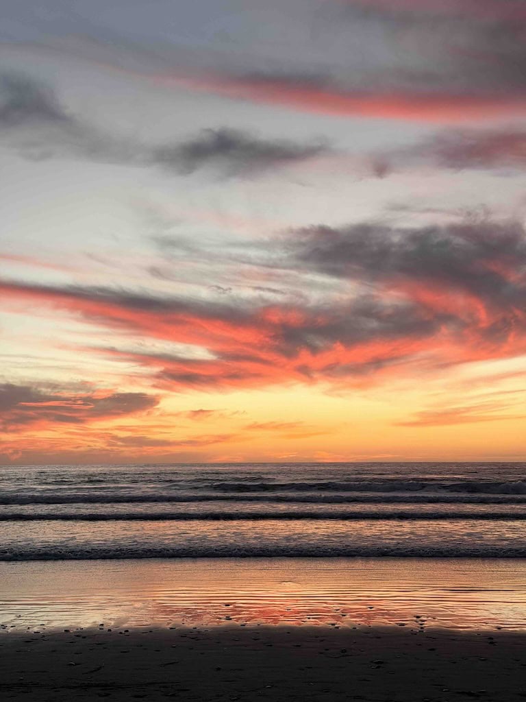 Sunset over the ocean with vibrant pink and orange hues reflecting on the water, creating a peaceful.