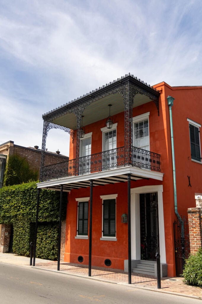 Bright orange building with black wrought iron balcony and white accents.