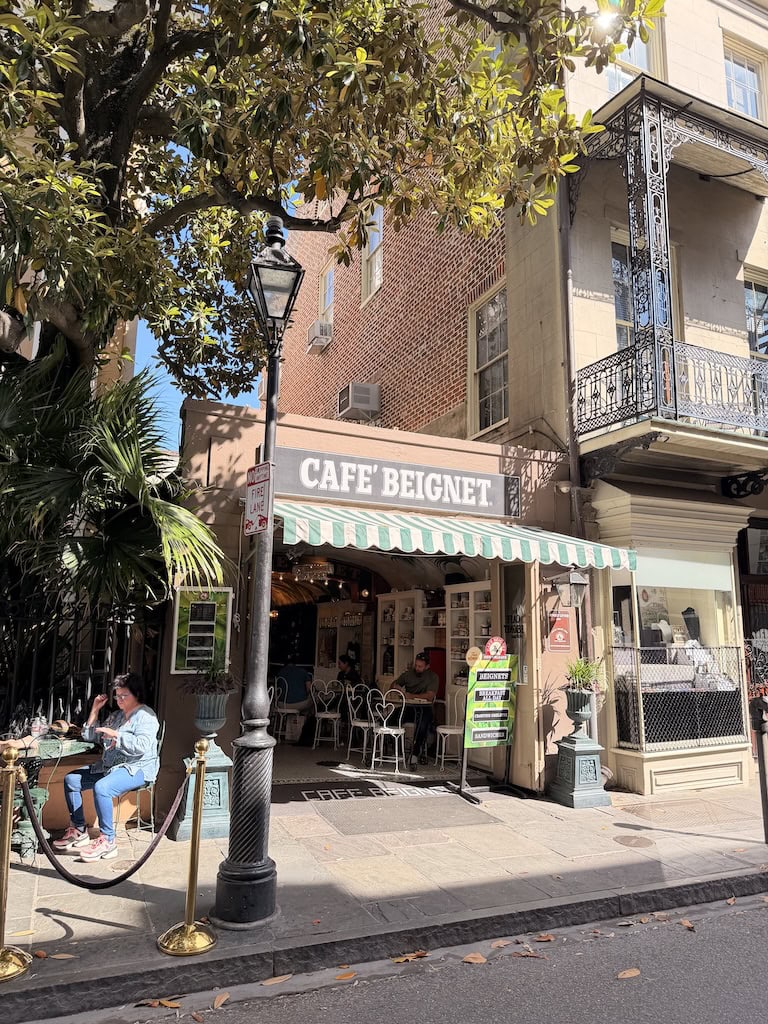 Charming cafe exterior with outdoor seating and striped awning in a city street.