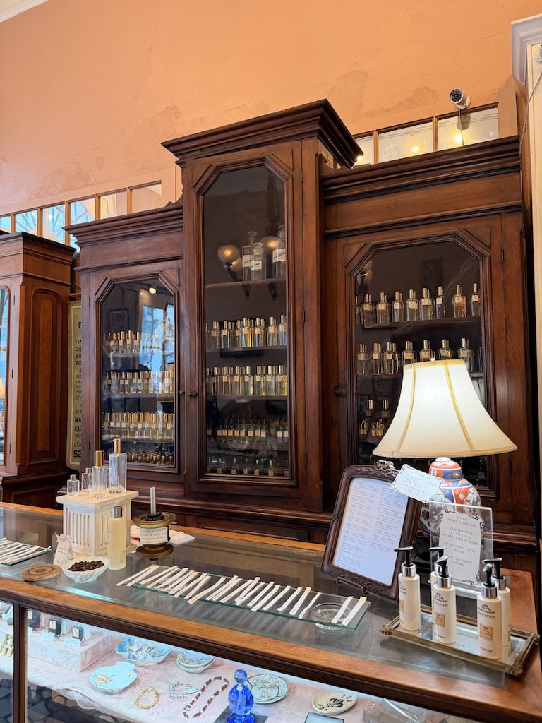 Antique wooden apothecary cabinet with glass doors showcasing bottles.