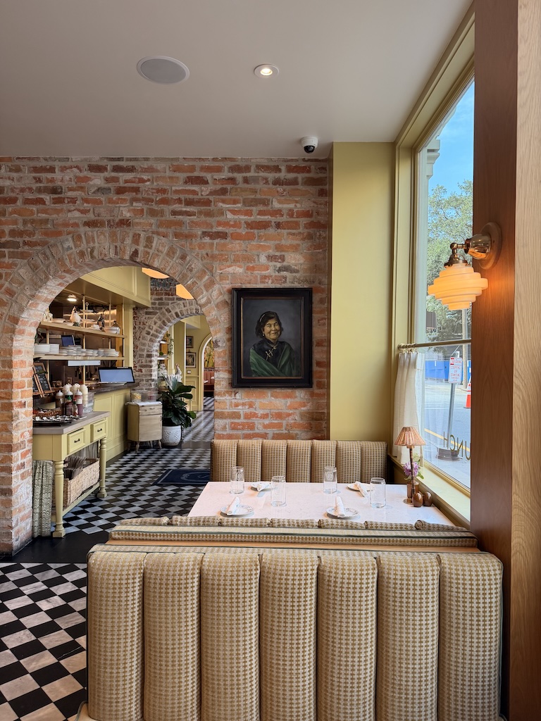 Cozy cafe corner with brick wall, portrait, and checkered floor.