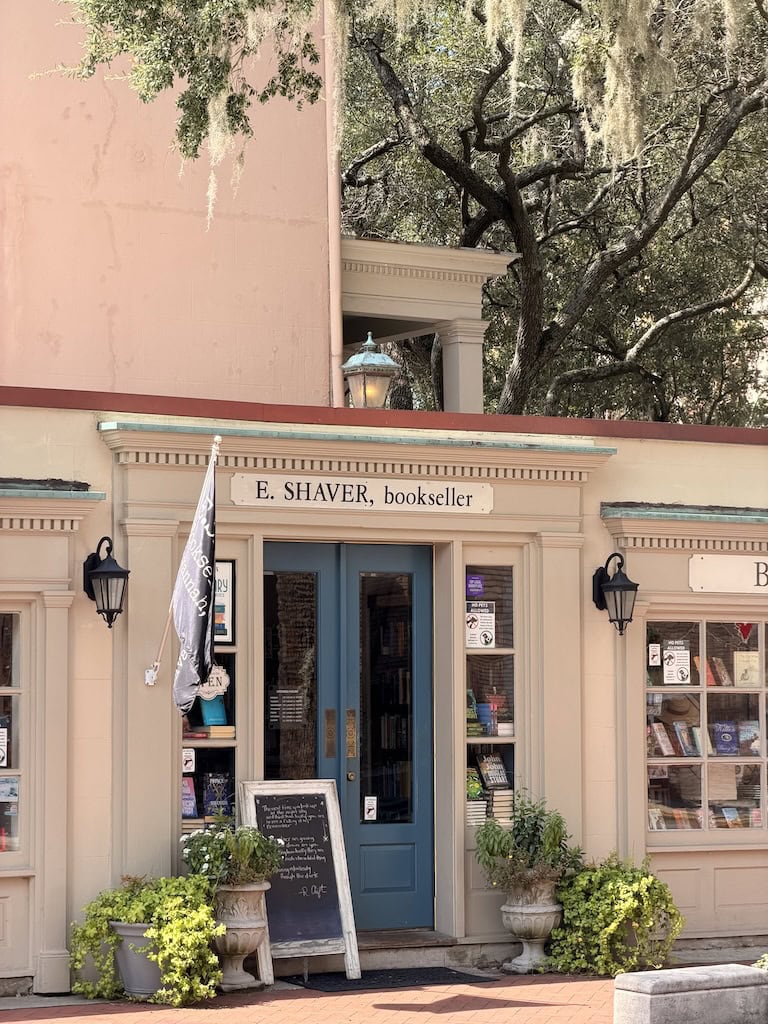 Cozy bookstore entrance with blue door, potted plants, and vintage signage.