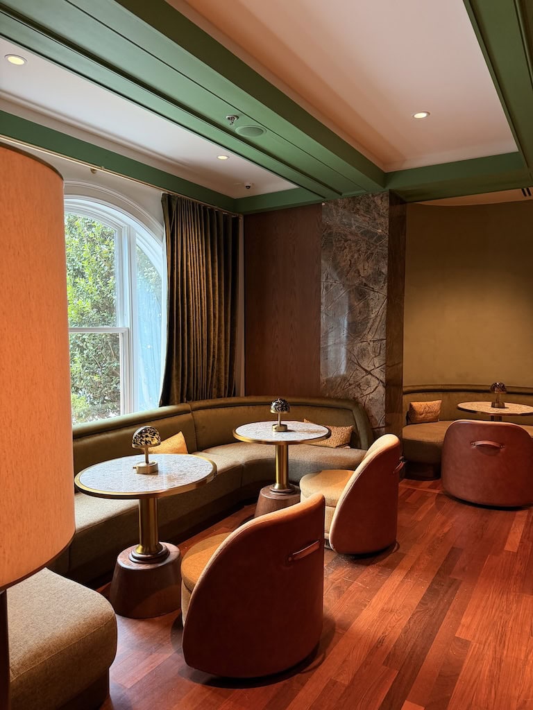 Stylish lounge with curved seating, round tables, and large window at Le Travel Style.