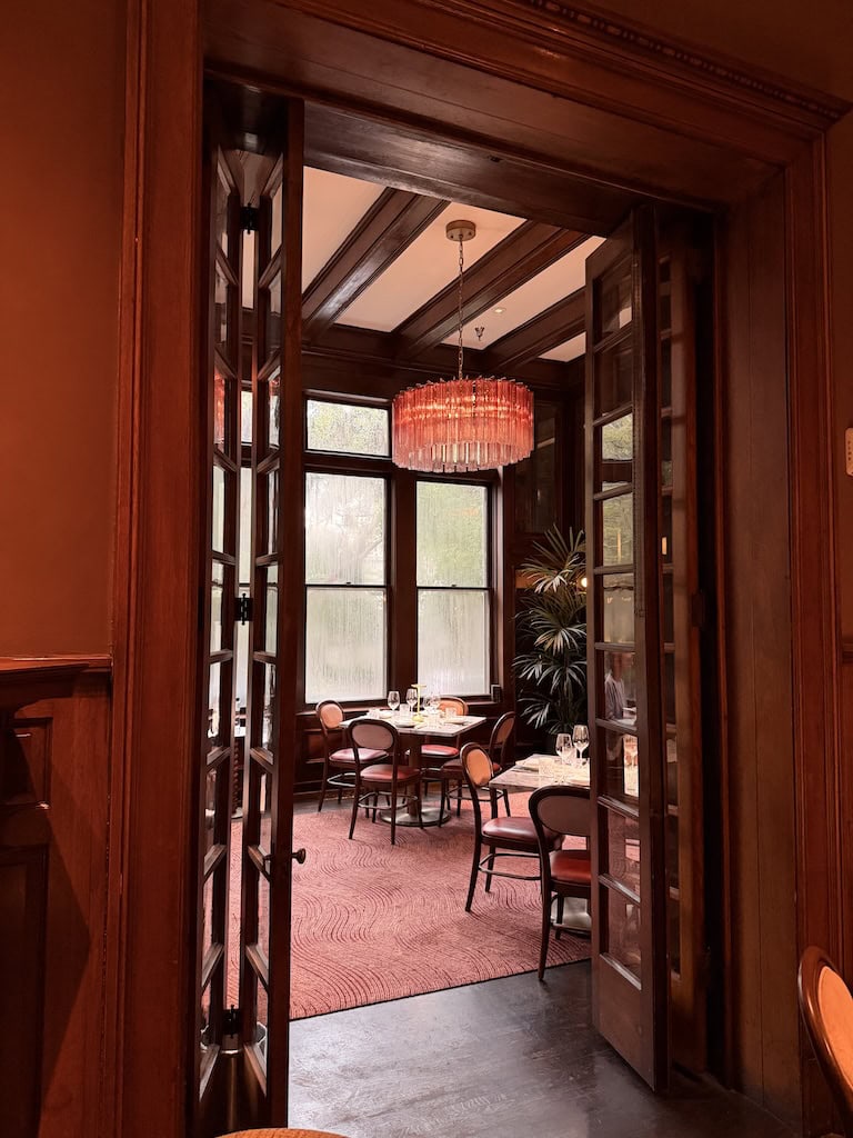 Charming vintage dining room with large windows and pink chandelier.