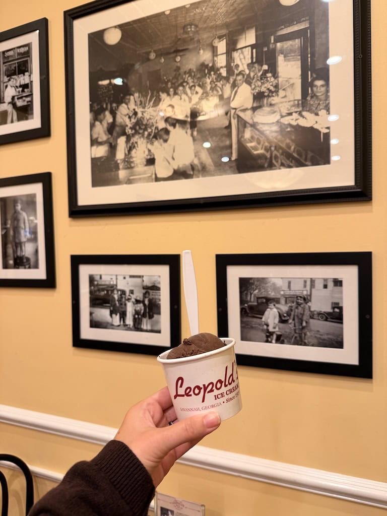 Person holding Leopolds ice cream cup in front of vintage photos.