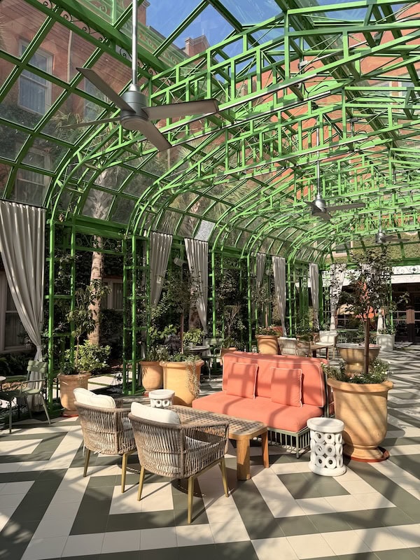 Modern greenhouse lounge with green metal framework and cozy seating.