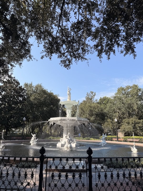 Beautiful historic fountain with statues in a lush park setting.