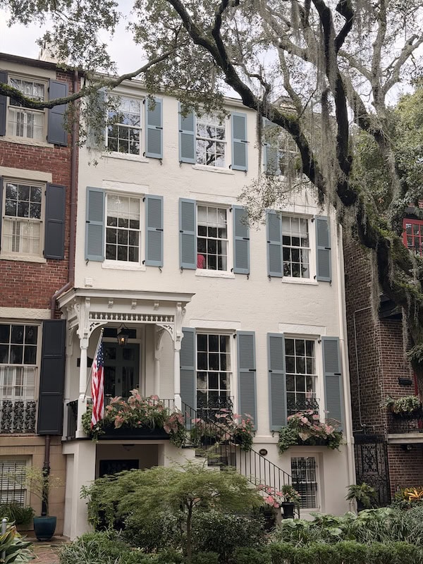 Historic townhouse with blue shutters and lush garden in Charleston.